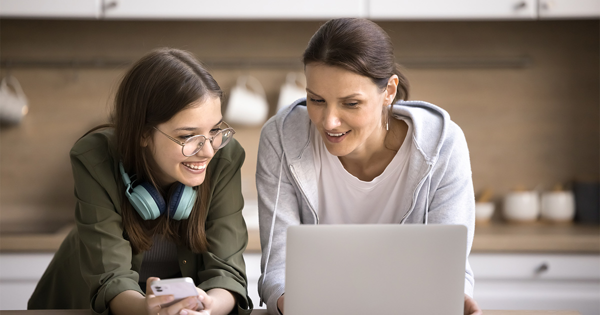 Two women review websites and apps on their laptops and smartphone devices. A mortgage banker must be aware of this kind of heavy tech use with their clients.